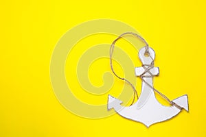 White wooden anchor figure on yellow background, top view. Space for text