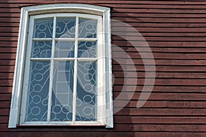 White wooden antique window on a wooden building. Old well-kept wooden house. Old Church and Windows with a cross