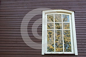 White wooden antique window on a wooden building. Old well-kept wooden house. Old Church and Windows with a cross