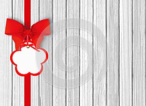 White wooden background with beautiful red bow with tag