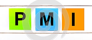 On a white wooden background there are three colorful bright stickers with text PMI Project Management Institute