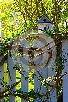 White wooden bird house on a picket fence post