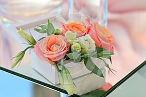 White wooden box with fresh flowers stands on a mirrored table