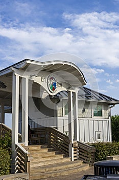 A white wooden buildings and a staircase at the entrance of Johnnie Mercer\'s Fishing Pier with blue sky and clouds