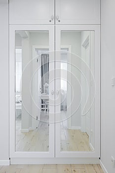 White wooden cabinet with a mirror in the hallway