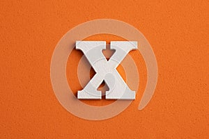White wooden capital letter X on orange foamy background
