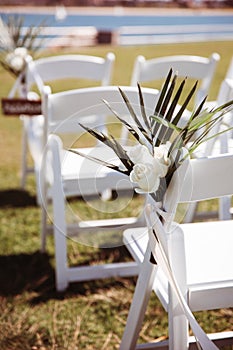 White wooden chair with rustic Reserved sign on green lawn . Outdoor wedding ceremony