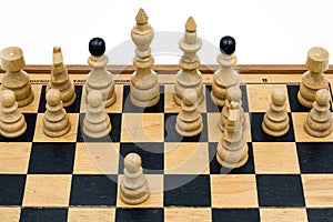 White wooden chess pieces arranged on a chessboard photo