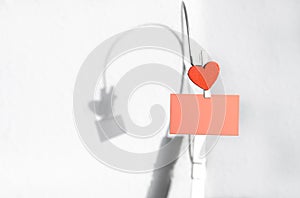 Clothespin with red heart shape clip on blank pink paper note