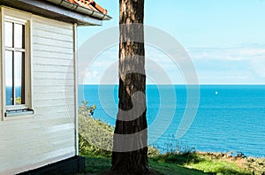 White wooden cottage with beautiful view over blue Baltic Sea.