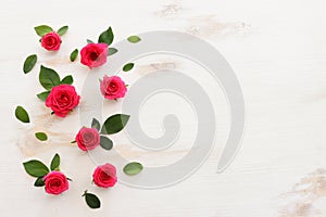 White wooden delicate background with pink roses and petals. Top view