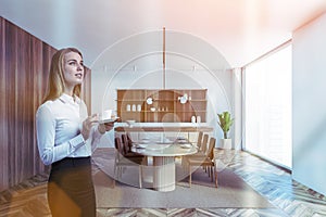 White wooden dining room with office woman with cup of tea, big windows