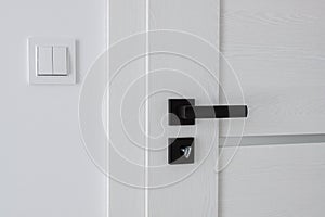 A white wooden door with a black metal handle