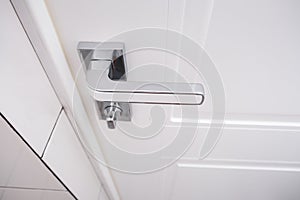 White wooden door with a chrome handle and safety security knob for privacy protection