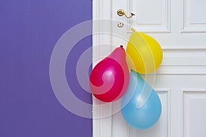 White wooden door decorated with three colorful balloons