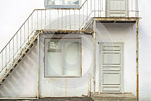 White wooden door and window in an old frame. Stairs to the second floor