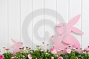 White wooden easter decoration with flowers and a pink bunny for