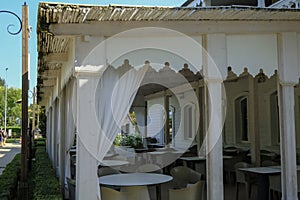 White Wooden Empty restaurant terrace with white  tables and chairs. Outdoors cafe on the city street. Urban lifestyle