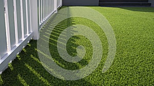 white wooden fence on green artificial turf surface in front yard of home