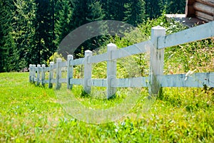 White wooden fence on a mountain meadow