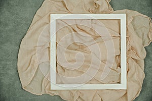 The white wooden frame arranges the elements on the fabric