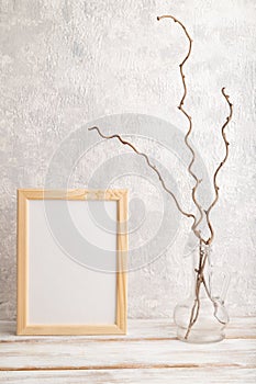 White wooden frame mockup with dried wine branch in glass on gray concrete background. Blank, vertical orientation, copy space