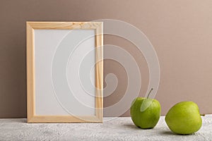White wooden frame mockup with green apple on beige paper background. Blank, vertical orientation, copy space