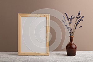 White wooden frame mockup with lavender in ceramic vase on beige paper background. Blank, vertical orientation, copy space