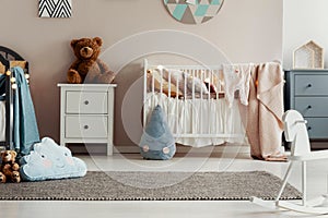 White wooden furniture in pastel scandinavian baby bedroom for twins