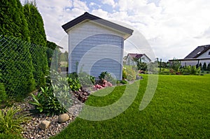 White wooden garden shed or hut with flowers and plants