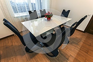 White wooden and glass round dining table with six chairs. Modern design, dining table and chairs in contemporary kitchen. Series