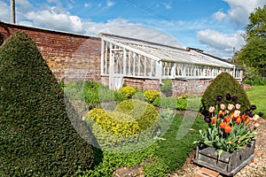 White wooden greenhouse in an English country manor house garden.