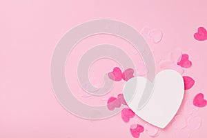 White wooden heart and paper hearts on pink pastel background top view. Greeting card for Valentines, Woman or Mothers Day.