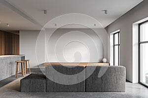 White and wooden kitchen interior with bar and sofa