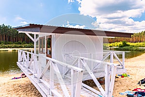 White, wooden lifeguard booth situated on sand beach next to the lake