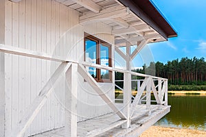 White, wooden lifeguard booth situated on sand beach next to the lake