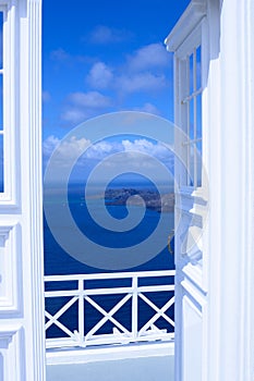 White wooden light open door. Behind the door is a beautiful turquoise sea and mountains.