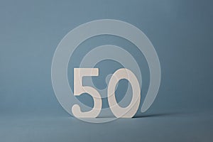 White wooden number fifty 50 on blue background.