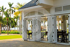 White wooden open pavilion in Thailand resort among palm trees and lawns. Wooden house