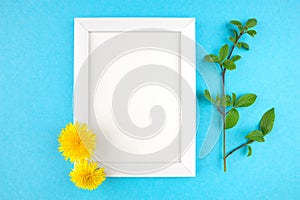 White wooden photo frame and flowers on blue background