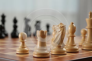 White wooden pieces on chess board, selective focus. Space for text