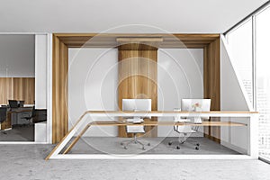 White and wooden reception desk with computers near window