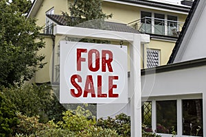 Wooden sign in front of a house with message For Rent, For Sale, and the german words for sale - zu verkaufen photo