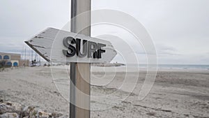 White wooden sign with the word surf near a surfers beach on the Costa Brava in Catalonia