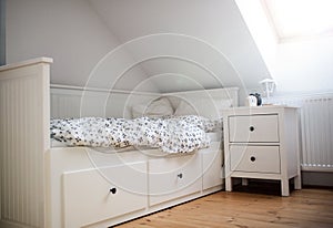 White wooden single bed wnd bedside table in bedroom at home.