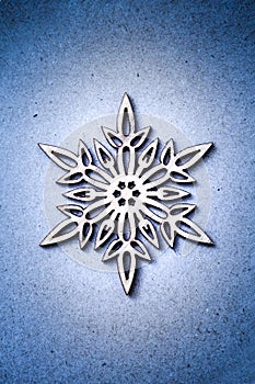 White wooden snowflake on blue craft paper