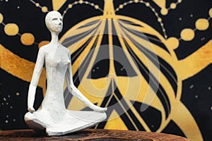A white wooden statue of a woman sat cross-legged against a karmic, cosmic space background - astral plain mysticism body and mind photo
