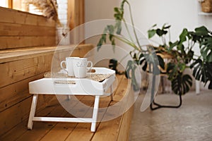 Close up of white tray with two cups on wooden steps