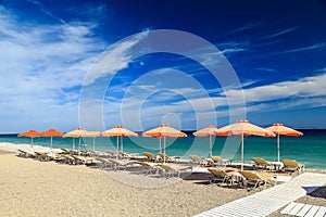 White wooden walkway on beach including umbrellas with deck chairs. Aegean Sea. Greece Rhodes. pebble beach