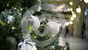 White wool balls and lights. New Year`s and abstract blurred shopping mall background with Christmas tree decorations.